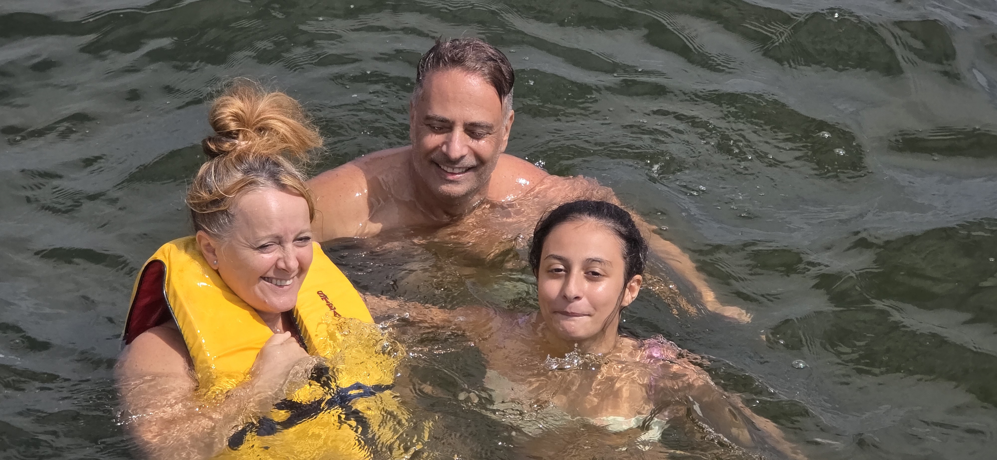 Family swimming in Barnegat Bay during private charter with yellow life jacket unforgettablecharter.com